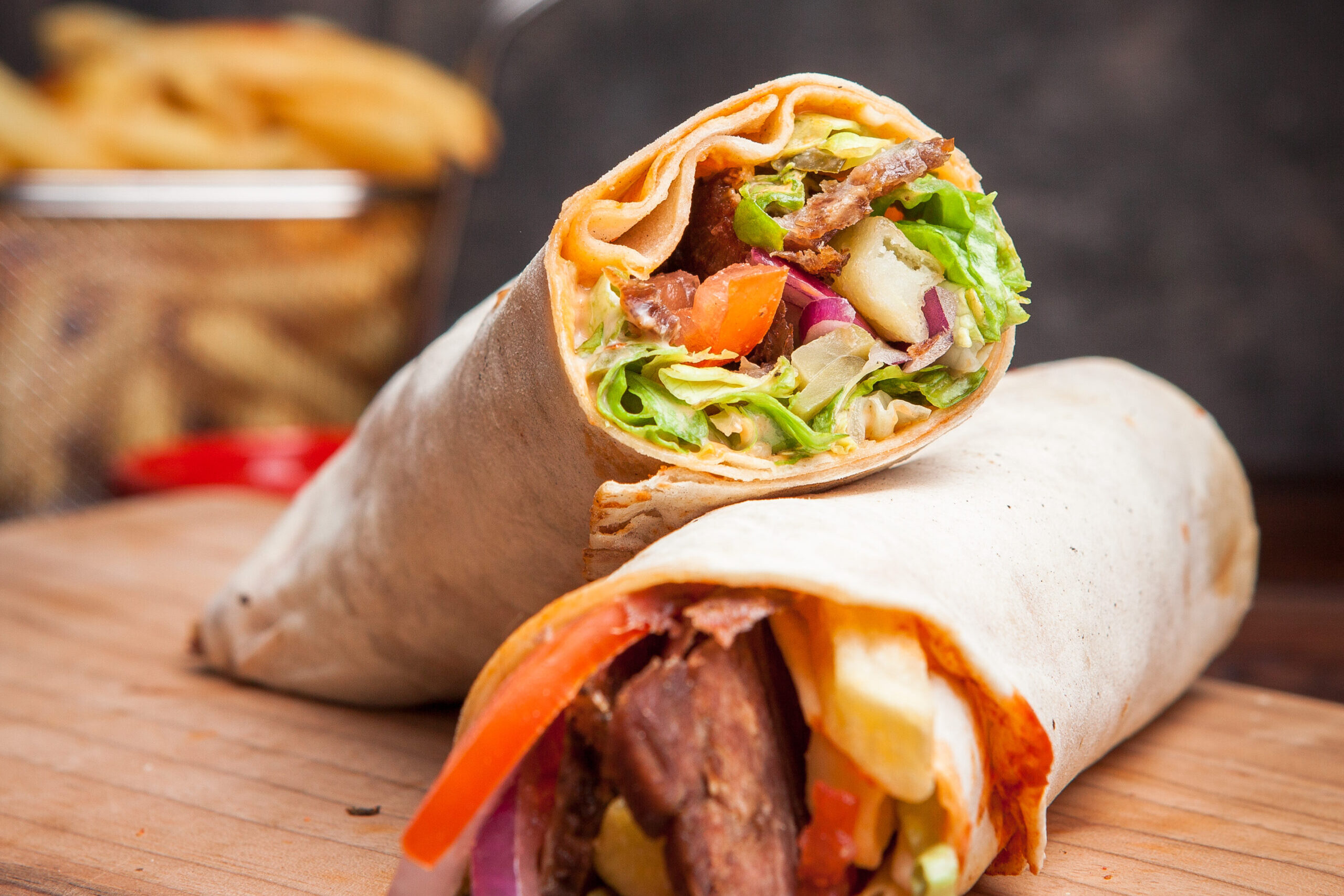 Side view shawarma with fried potatoes in board cookware on stone background